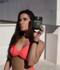 Mujer fitness al aire libre sosteniendo suplemento Life Pro