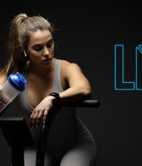 Mujer deportista descansando con shaker Life Pro en bicicleta estática