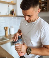 Hombre preparando batido en cocina con shaker deportivo